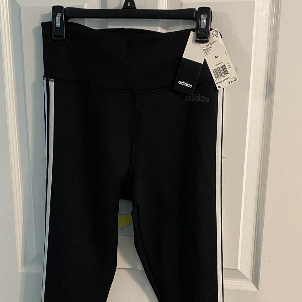 Women’s stretch leggings Adidas black. Three stripes on the side of each leg.